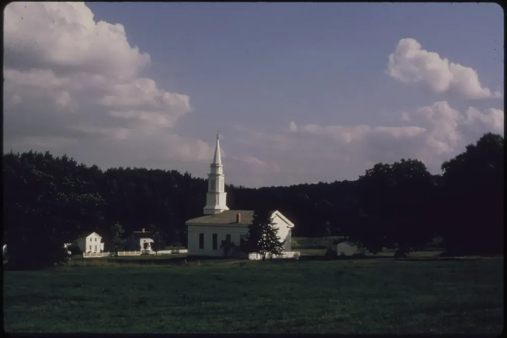 White church steeple and historic buildings across an open field at Hale Homestead in Bath Township, Ohio