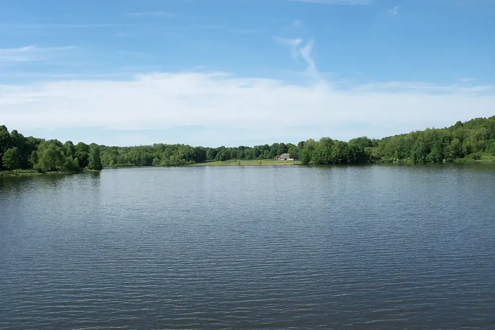 Calm Silver Creek Lake edged by green woods under a summer sky in Norton, Ohio