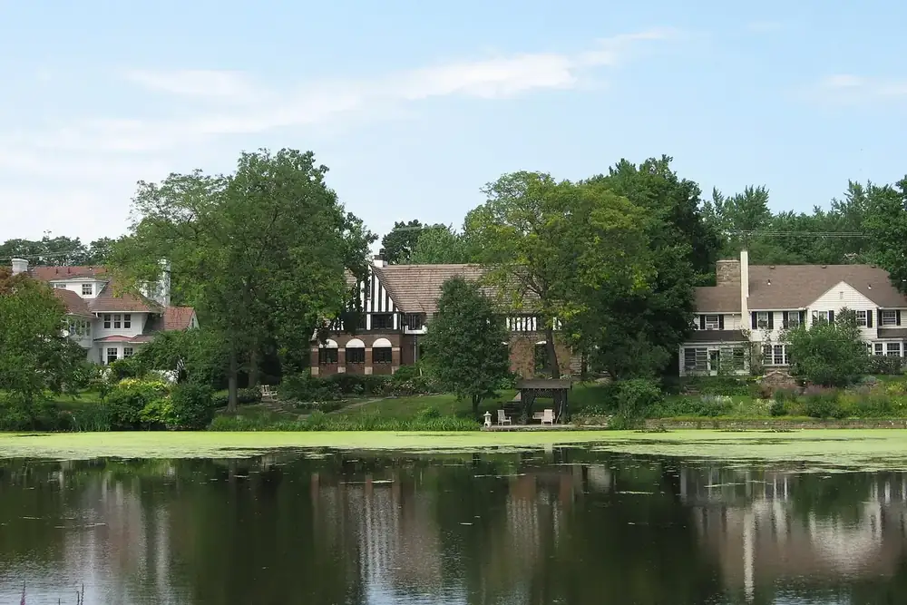 Tudor and colonial houses among tall trees across Green Lake in Shaker Heights, Ohio