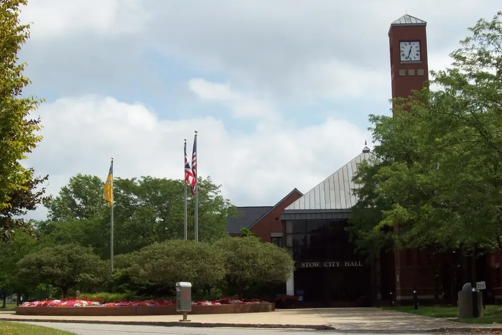 Stow City Hall with its brick clock tower and flagpoles in Stow, Ohio