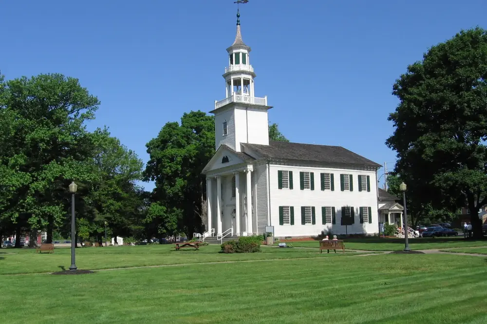 White historic church with a tall steeple on the green of Tallmadge Circle, Ohio
